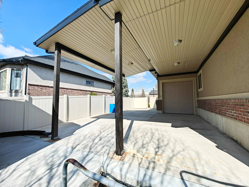 View of patio / terrace featuring an attached garage, fence, and driveway
