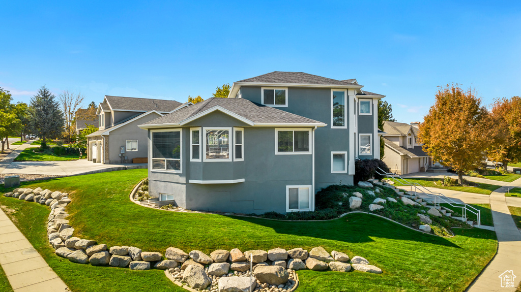 View of side of property featuring a lawn, stucco siding, and a garage