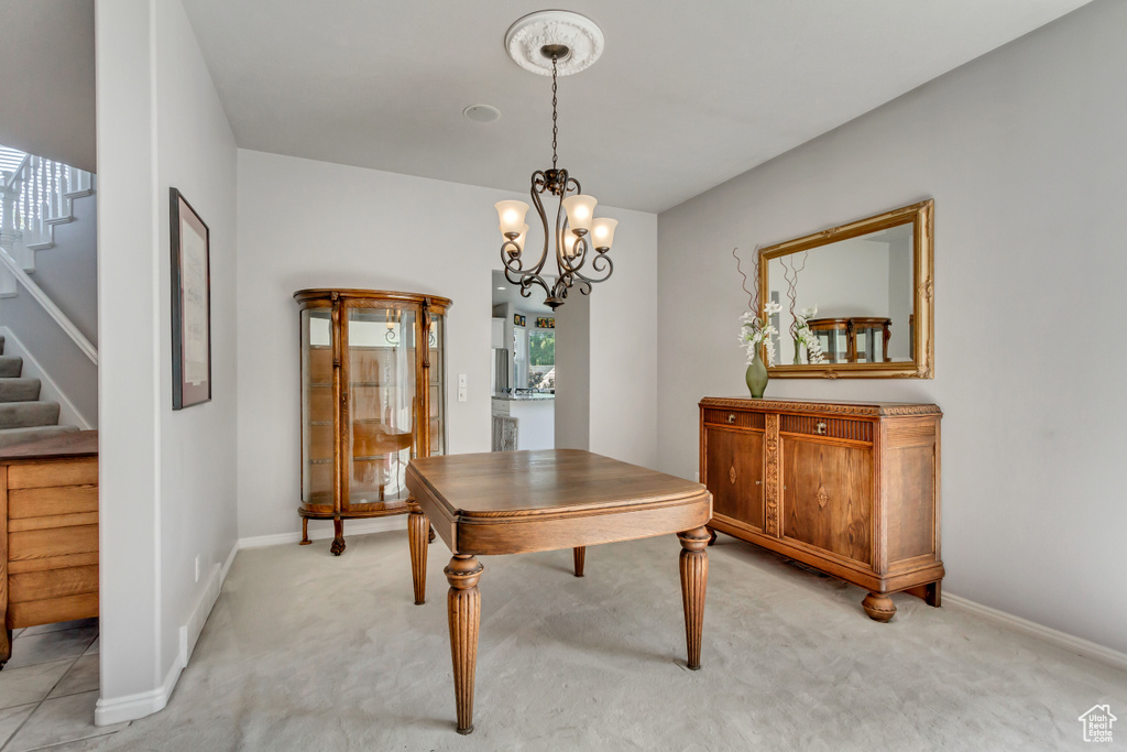Dining room featuring light carpet, stairs, baseboards, and a chandelier