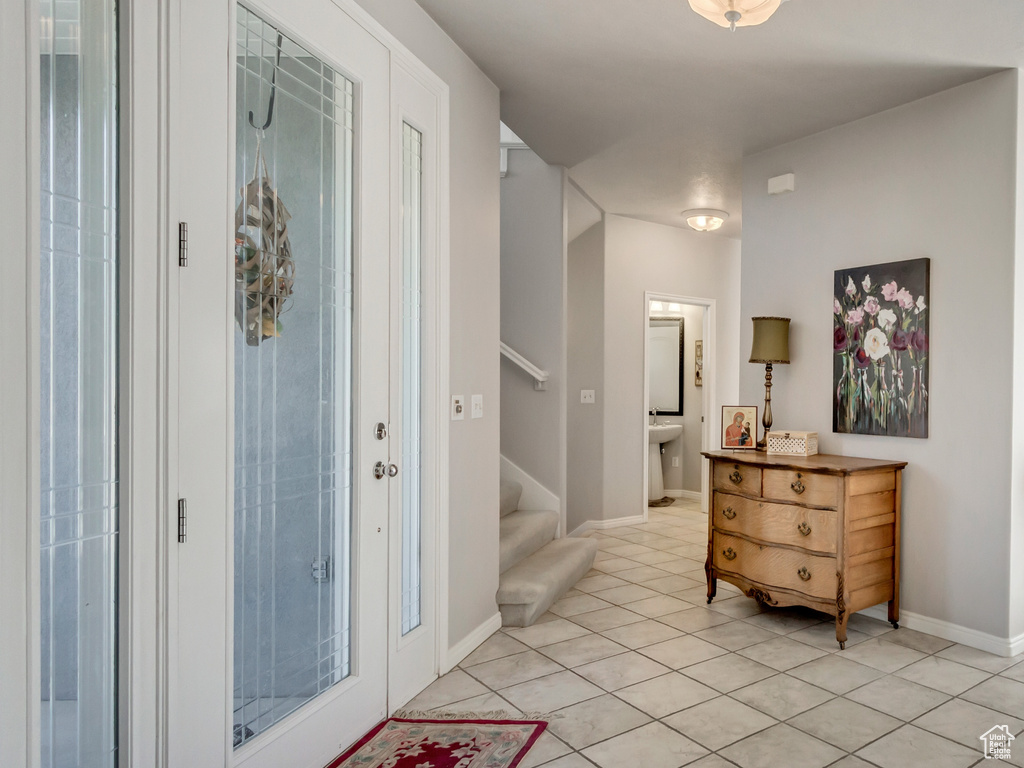 Entrance foyer featuring baseboards, stairs, light tile patterned floors, and light carpet