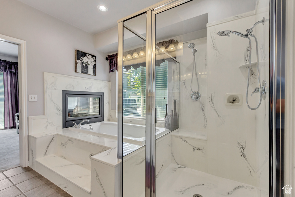Bathroom featuring plenty of natural light, a garden tub, and a marble finish shower
