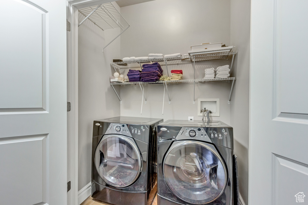 Clothes washing area featuring washing machine and clothes dryer, baseboards, and laundry area