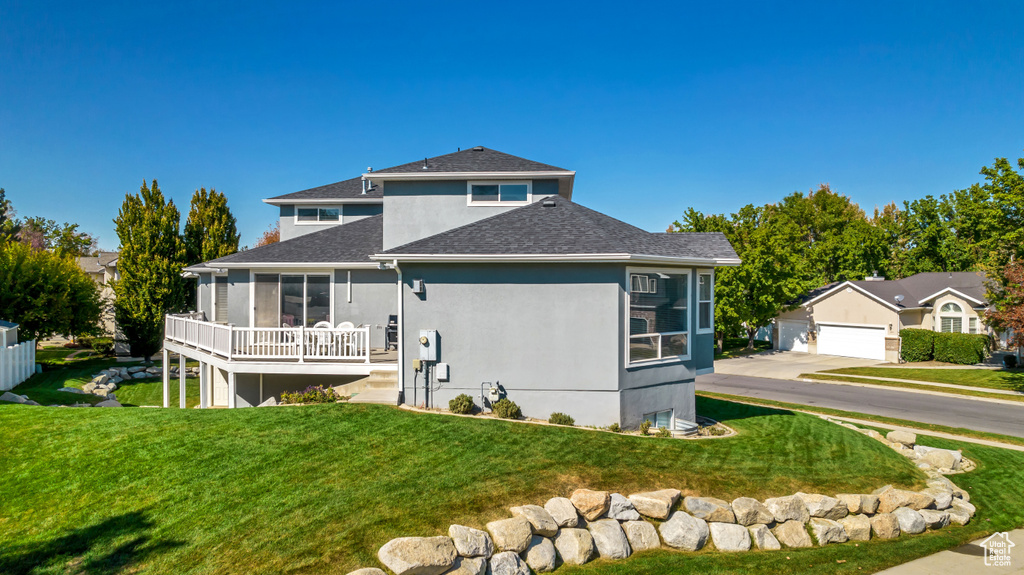 View of front of house with stucco siding, an outdoor structure, and a front yard
