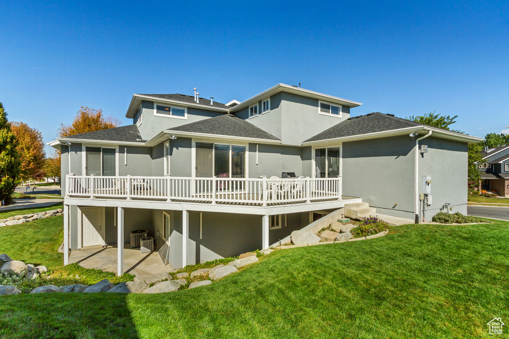 Back of house featuring stucco siding, roof with shingles, a deck, central AC, and a yard