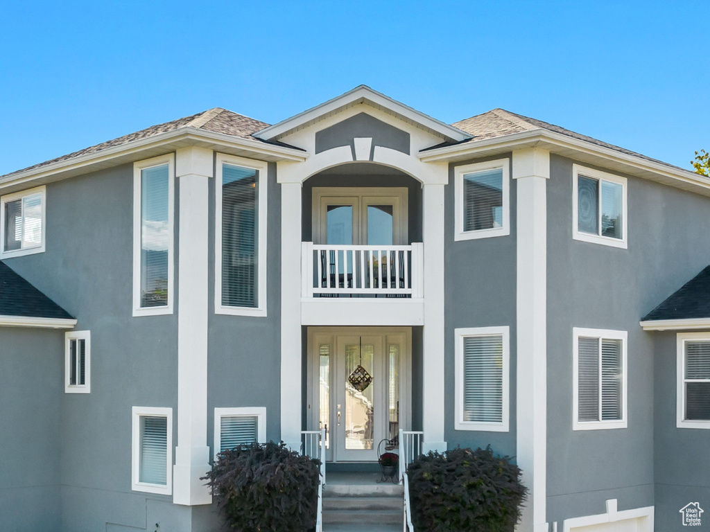 View of front of property featuring concrete driveway, stucco siding, stairs, a balcony, and a garage