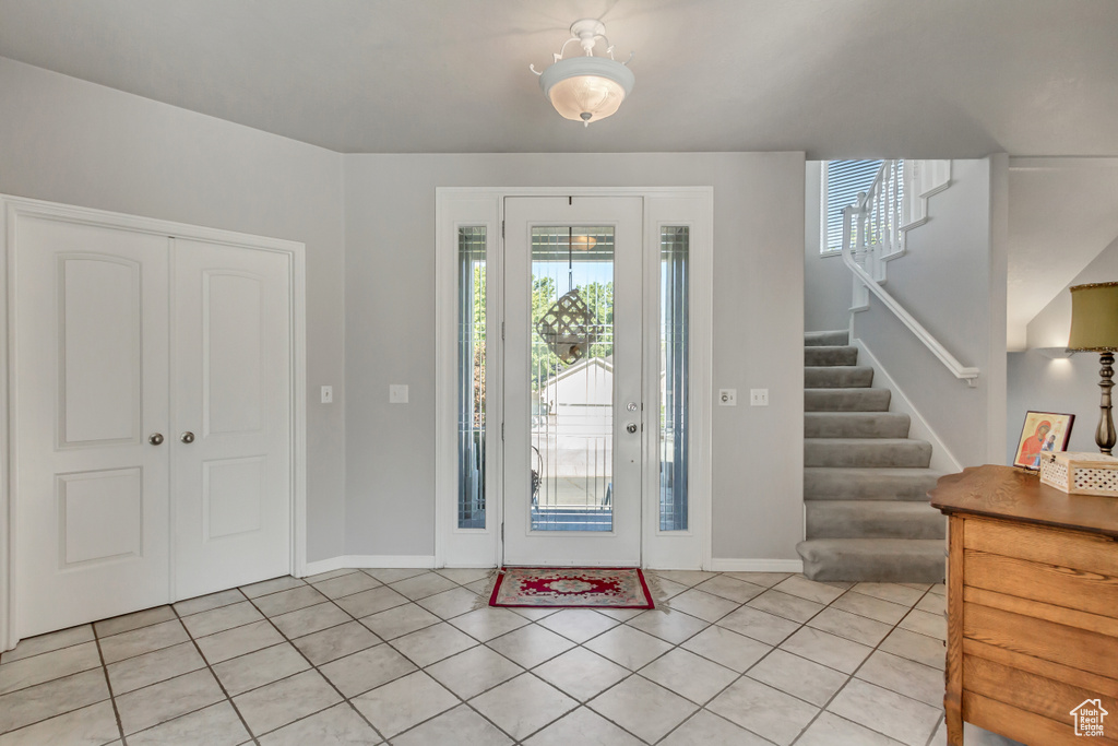 Entrance foyer featuring light tile patterned flooring, baseboards, and stairway
