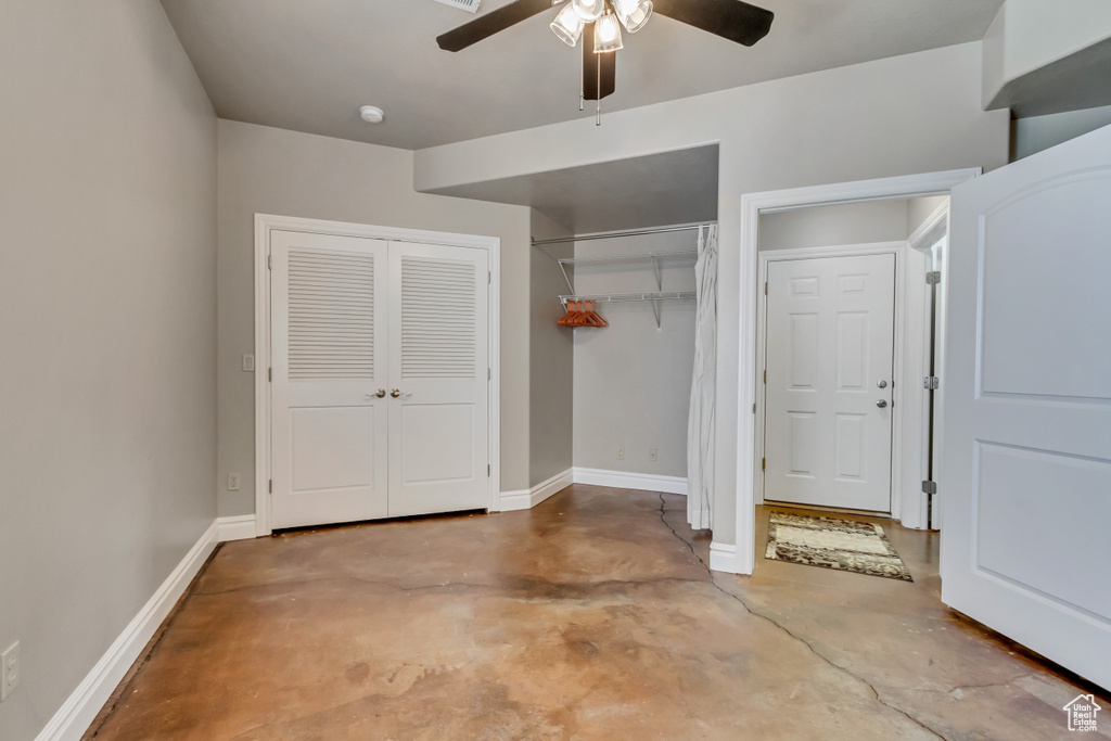 Unfurnished bedroom with baseboards, concrete floors, and a ceiling fan