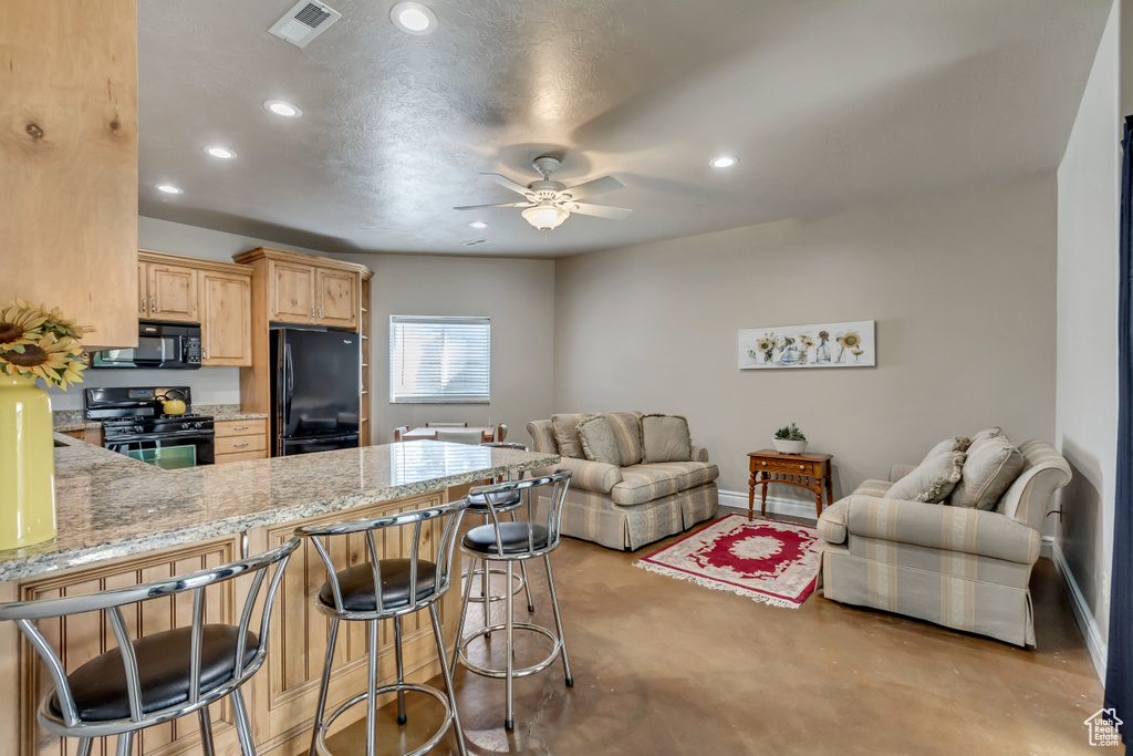Kitchen with finished concrete floors, ceiling fan, visible vents, light brown cabinets, and black appliances