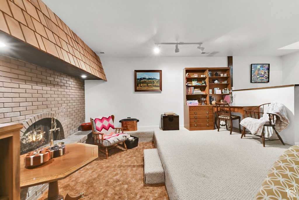 Carpeted living area with baseboards, a fireplace, and rail lighting