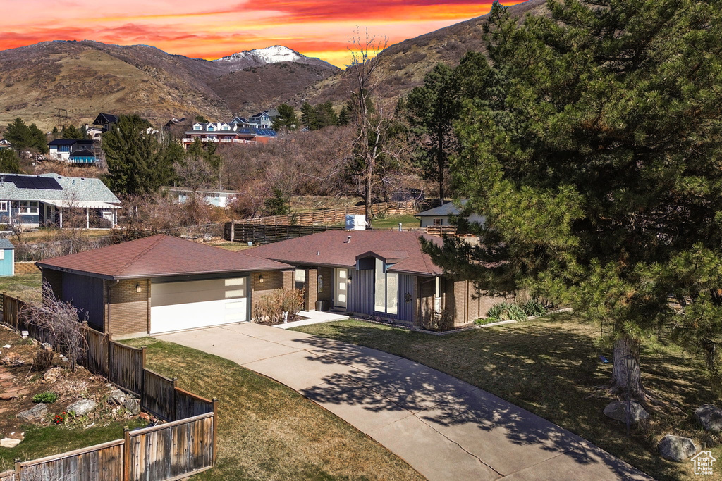 View of front of house featuring a garage, driveway, a mountain view, and fence