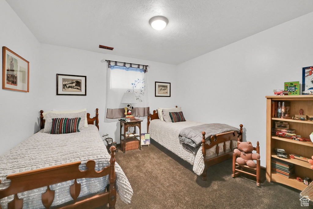 Carpeted bedroom featuring visible vents and a textured ceiling