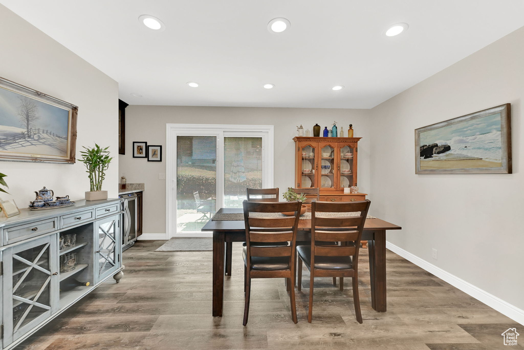 Dining room with wood finished floors, beverage cooler, baseboards, and recessed lighting