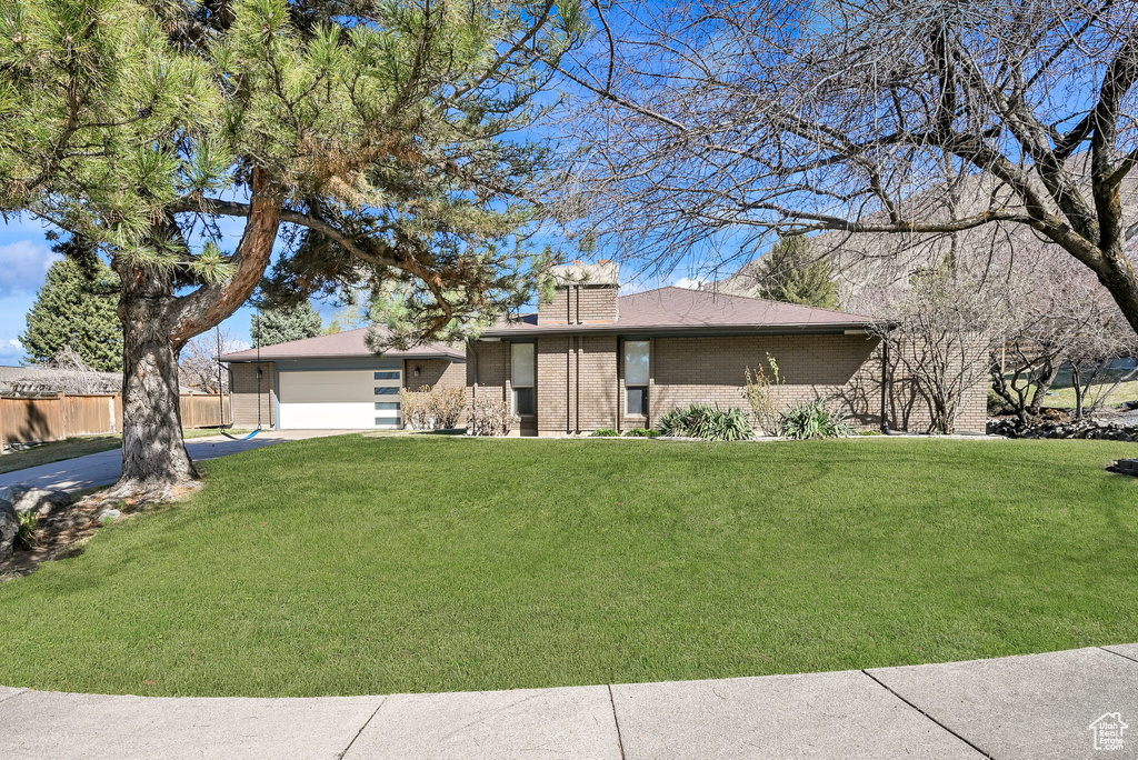 View of front of home with brick siding, driveway, a front lawn, and an attached garage