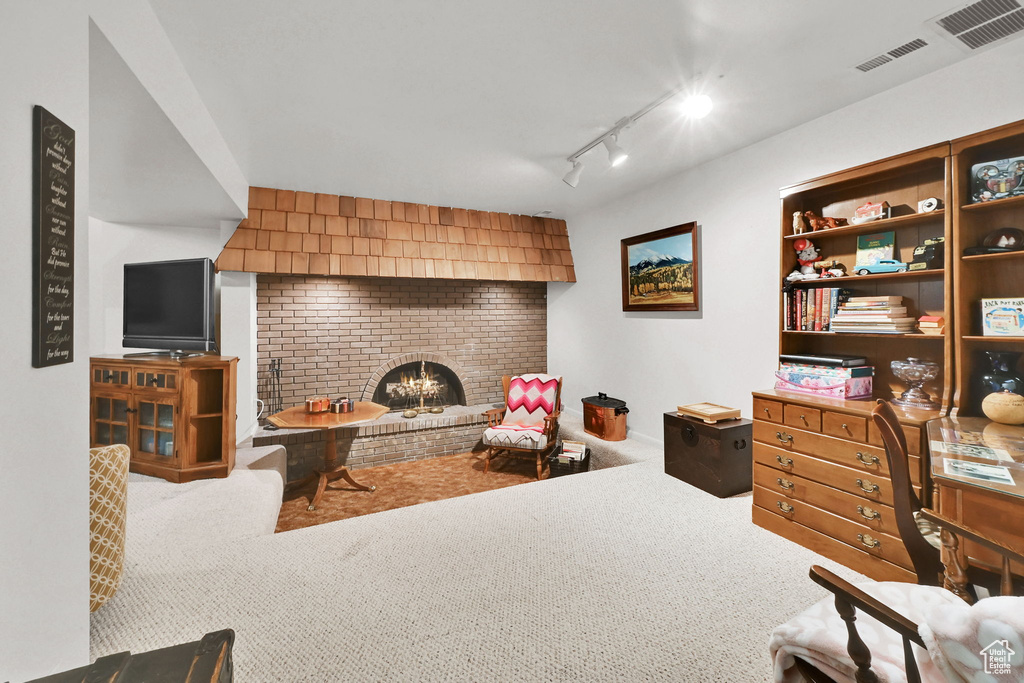 Living area featuring rail lighting, carpet flooring, visible vents, and a brick fireplace