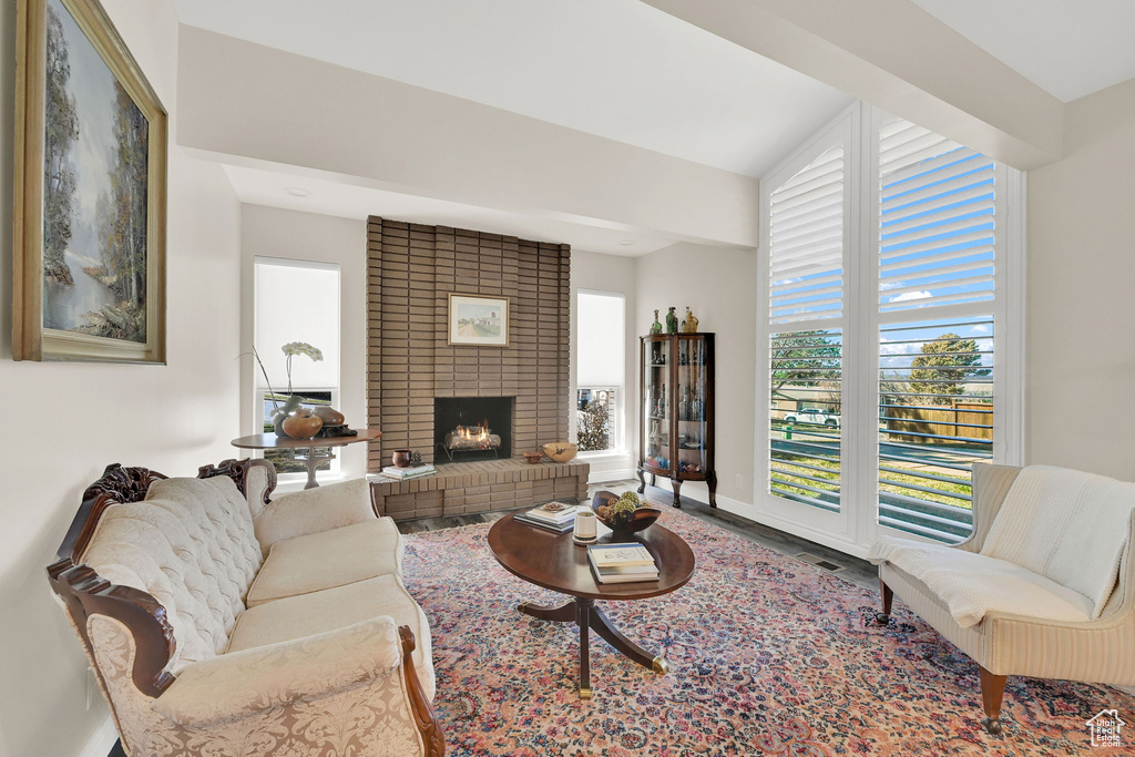 Living room with baseboards, wood finished floors, and a brick fireplace