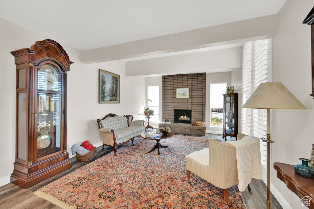 Living room with baseboards, a fireplace, wood finished floors, and beamed ceiling