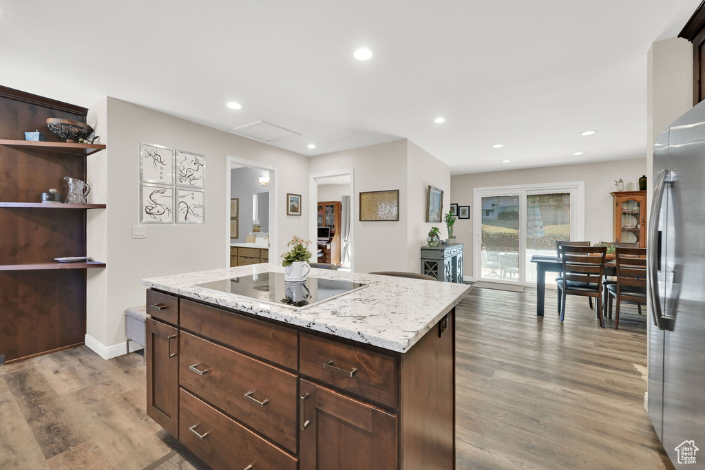 Kitchen with black electric cooktop, wood finished floors, recessed lighting, a kitchen island, and freestanding refrigerator