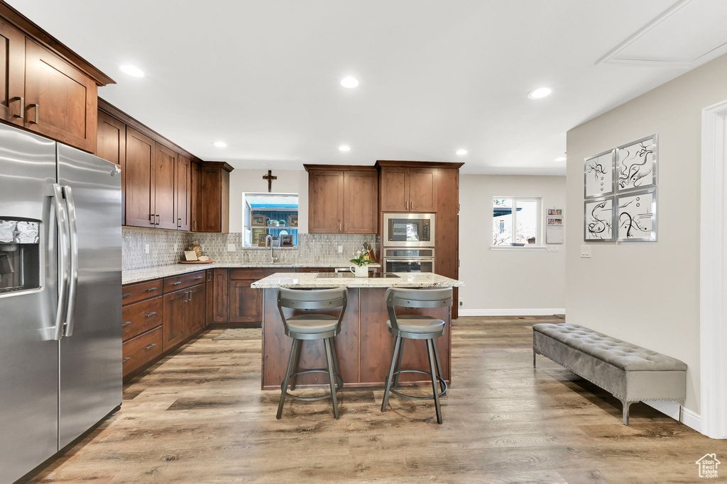 Kitchen featuring backsplash, stainless steel appliances, light wood finished floors, and a wealth of natural light