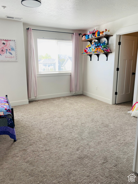 Unfurnished bedroom with a textured ceiling, carpet flooring, baseboards, and visible vents