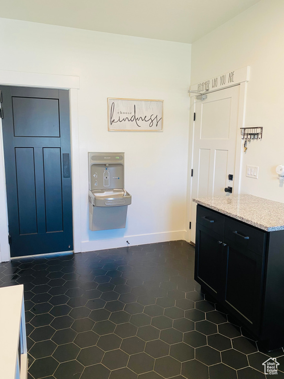 Interior space with dark tile patterned floors, baseboards, and light stone countertops