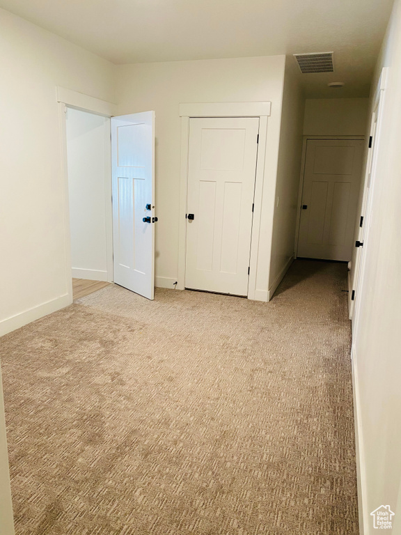 Empty room featuring light colored carpet, baseboards, and visible vents