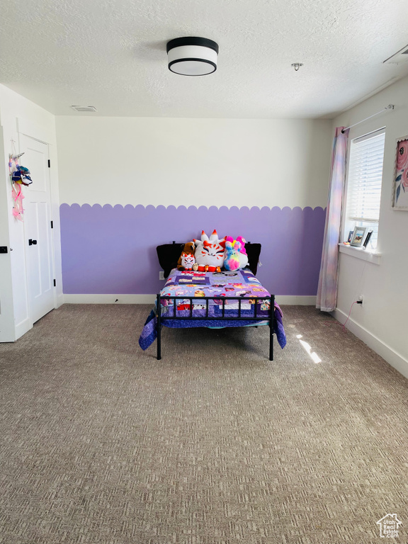 Bedroom featuring a textured ceiling, carpet flooring, and visible vents