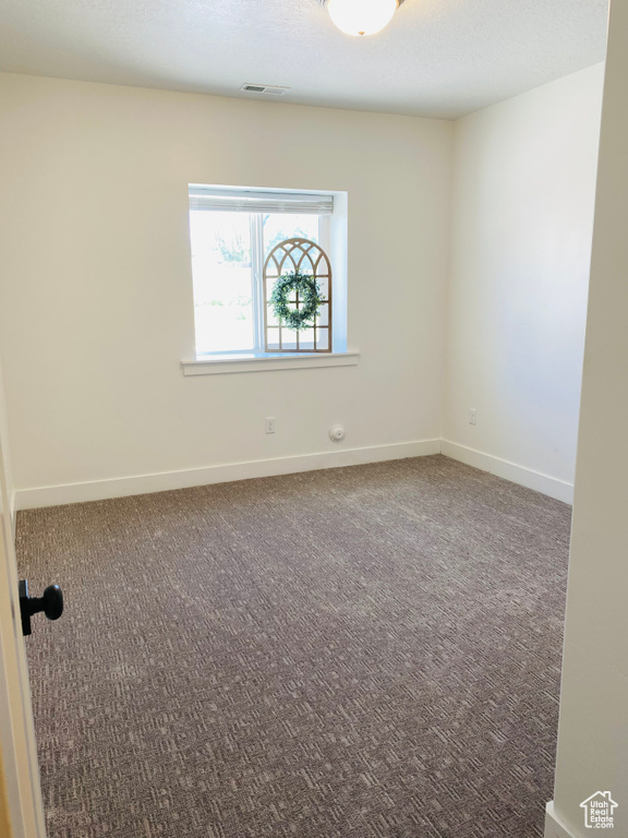 Empty room featuring baseboards and carpet flooring