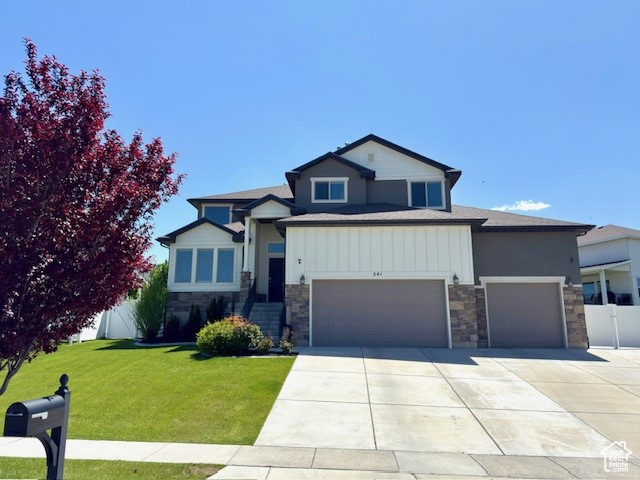 View of front of property with stone siding, driveway, an attached garage, and board and batten siding