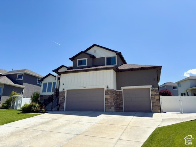 View of front of house featuring stone siding, driveway, and an attached garage