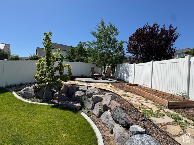 Fenced backyard featuring a patio and a vegetable garden