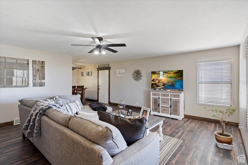 Living area featuring a textured ceiling, visible vents, baseboards, wood finished floors, and a ceiling fan