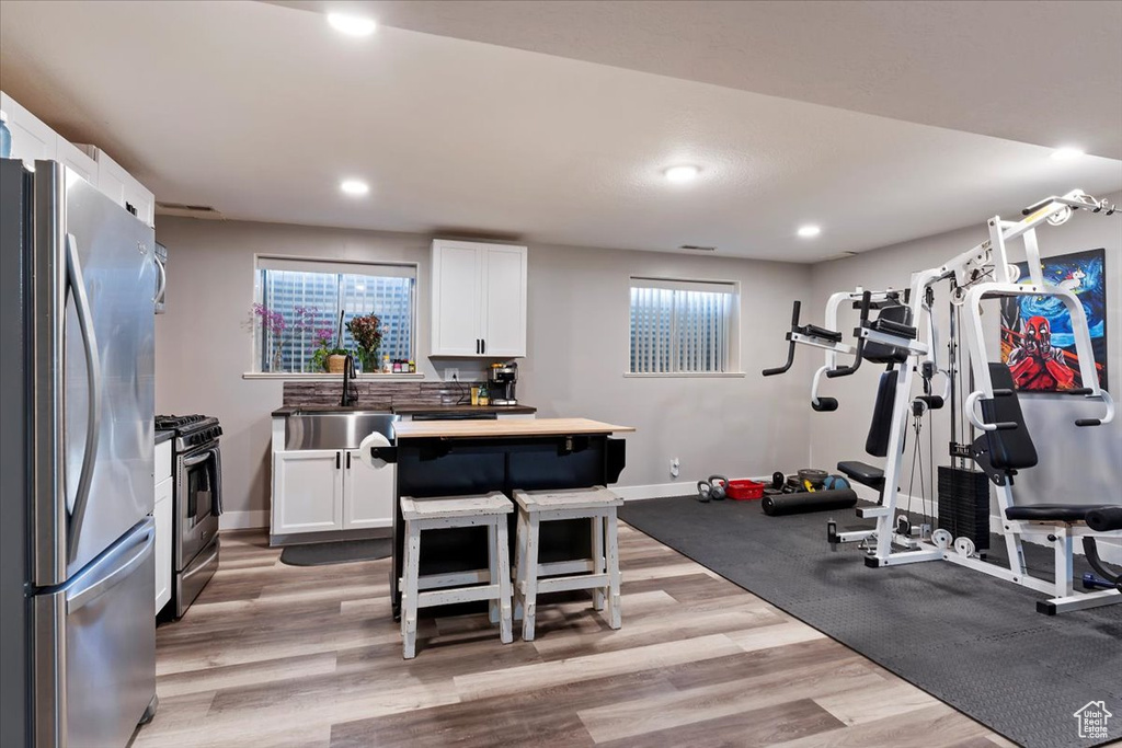 Workout area with a sink, baseboards, light wood finished floors, and recessed lighting