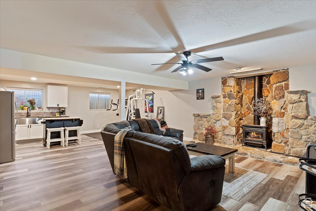 Living room with a textured ceiling, ceiling fan, and light wood-type flooring