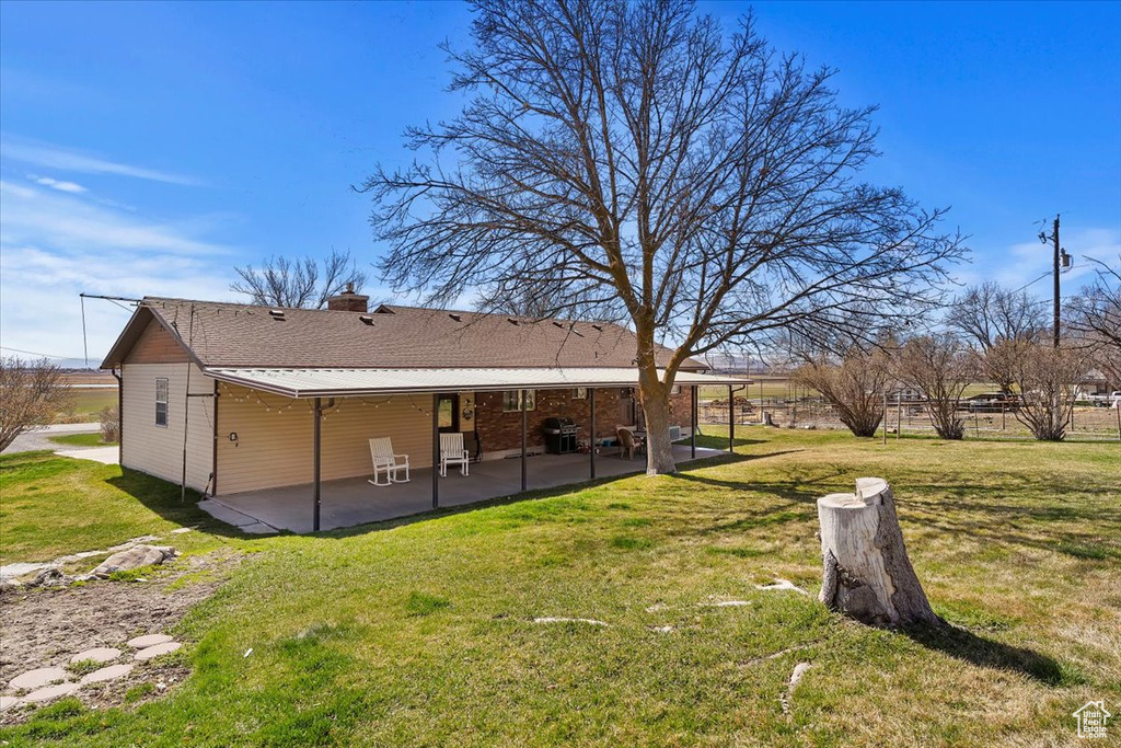Rear view of house with a chimney, a yard, and a patio area