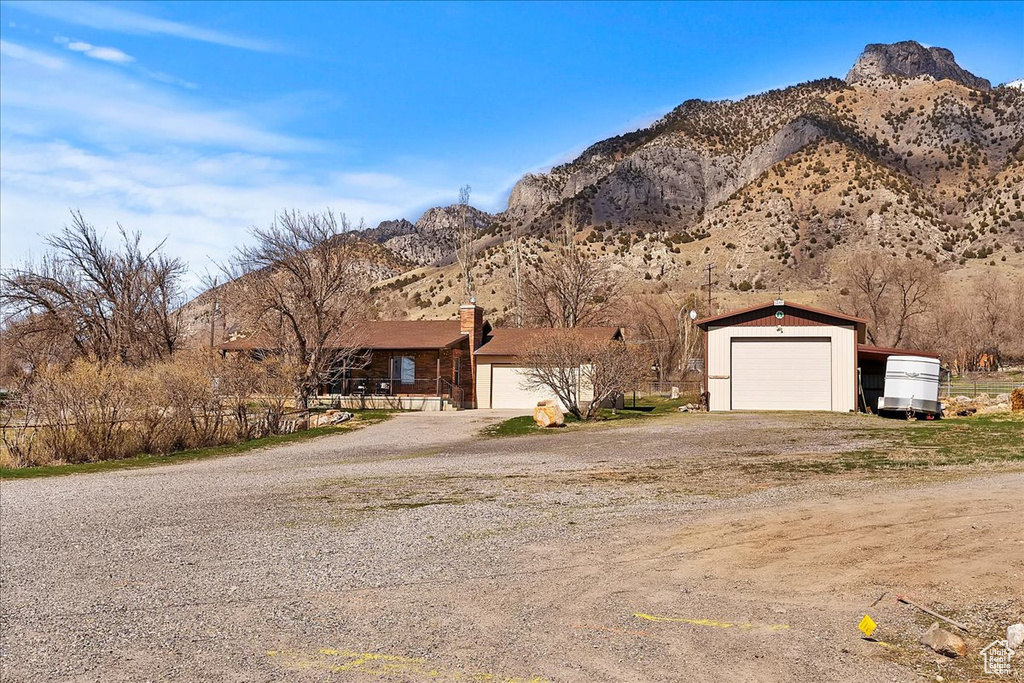 View of front of home with a garage, an outbuilding, a mountain view, and a chimney