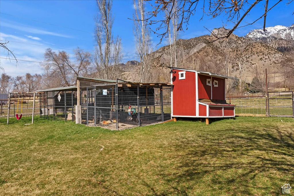 View of poultry coop with fence, a mountain view, and a yard