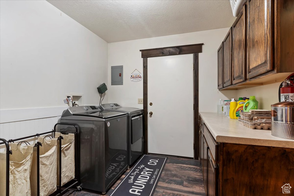 Laundry area with electric panel, washer and clothes dryer, a textured ceiling, dark wood finished floors, and cabinet space