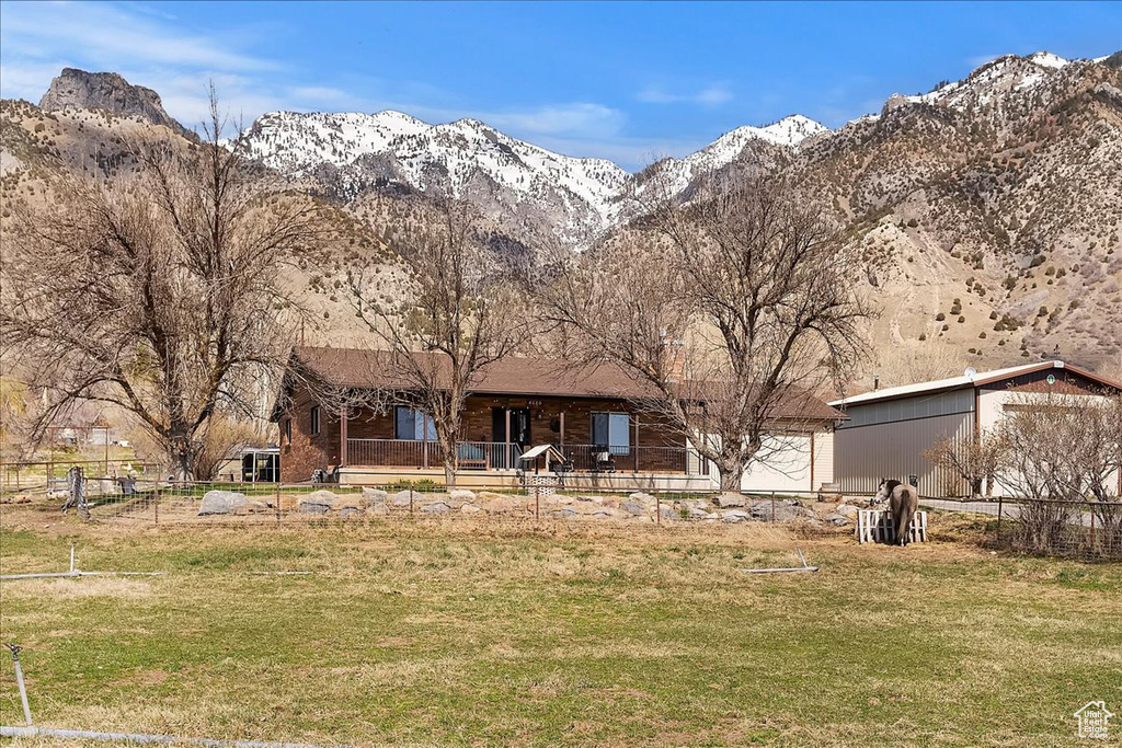 Back of property with fence, a mountain view, and a yard