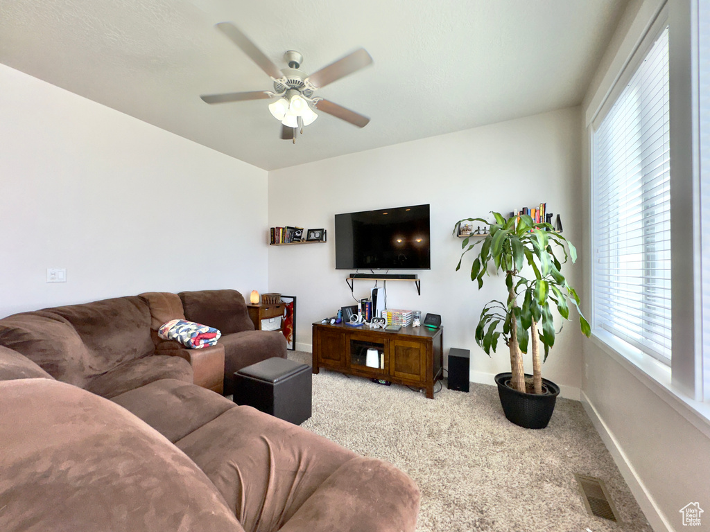 Living area featuring baseboards, visible vents, carpet, and a ceiling fan