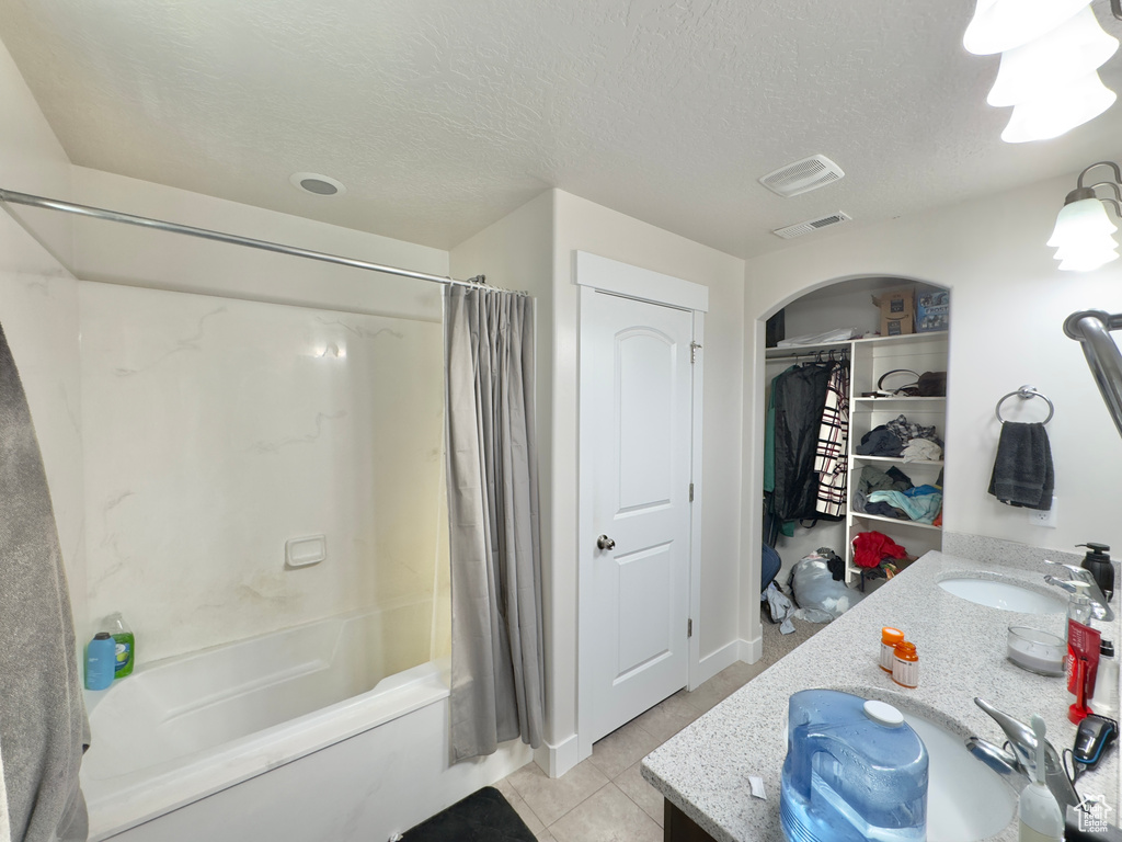 Full bath with tile patterned flooring, vanity, a textured ceiling, visible vents, and shower / bath combo