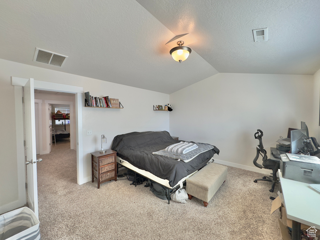 Bedroom with light colored carpet, visible vents, a textured ceiling, and vaulted ceiling