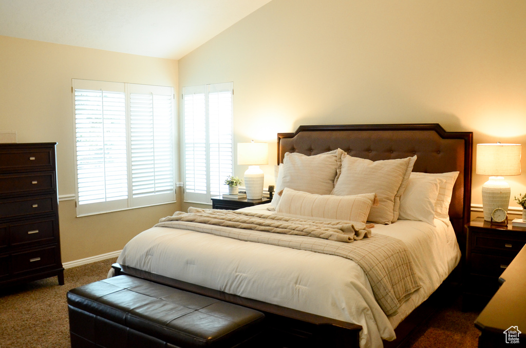 Bedroom with baseboards, lofted ceiling, and dark carpet