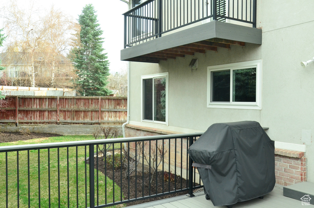 Wooden terrace featuring a grill, a lawn, and fence