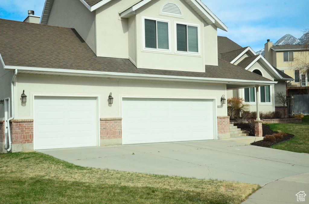 View of front of house with a garage, concrete driveway, brick siding, stucco siding, and a shingled roof
