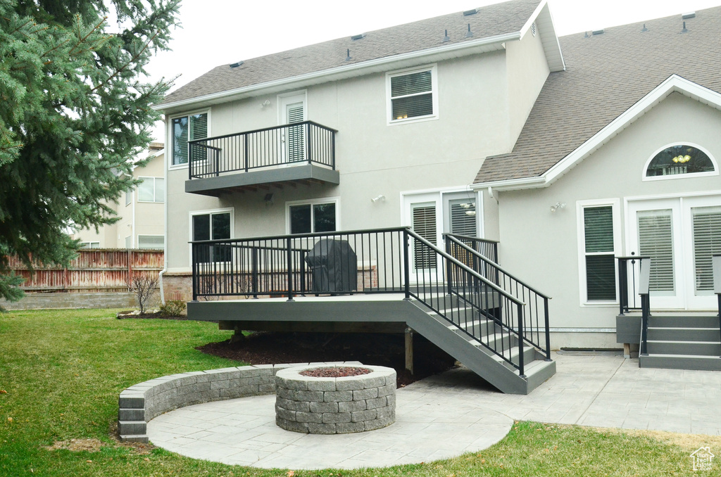 Back of property with a fire pit, stucco siding, and a yard