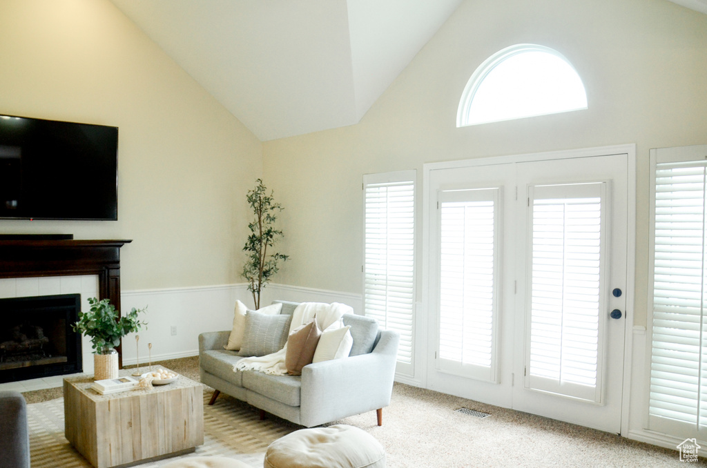 Living room featuring light colored carpet, high vaulted ceiling, a fireplace, and visible vents