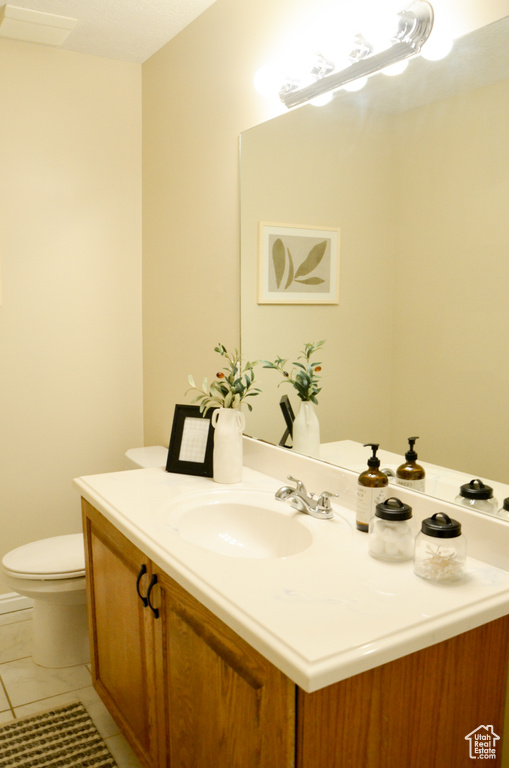 Half bathroom featuring tile patterned floors, vanity, and toilet