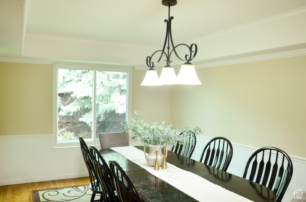 Dining area featuring a notable chandelier, crown molding, baseboards, and wood finished floors