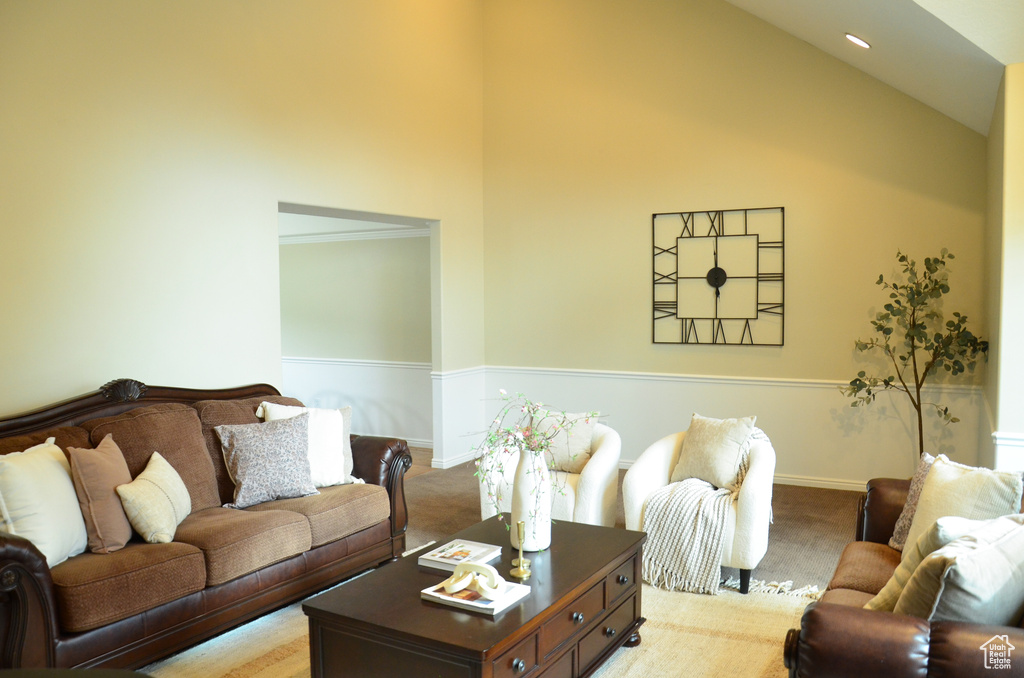 Living area featuring light carpet, high vaulted ceiling, and baseboards