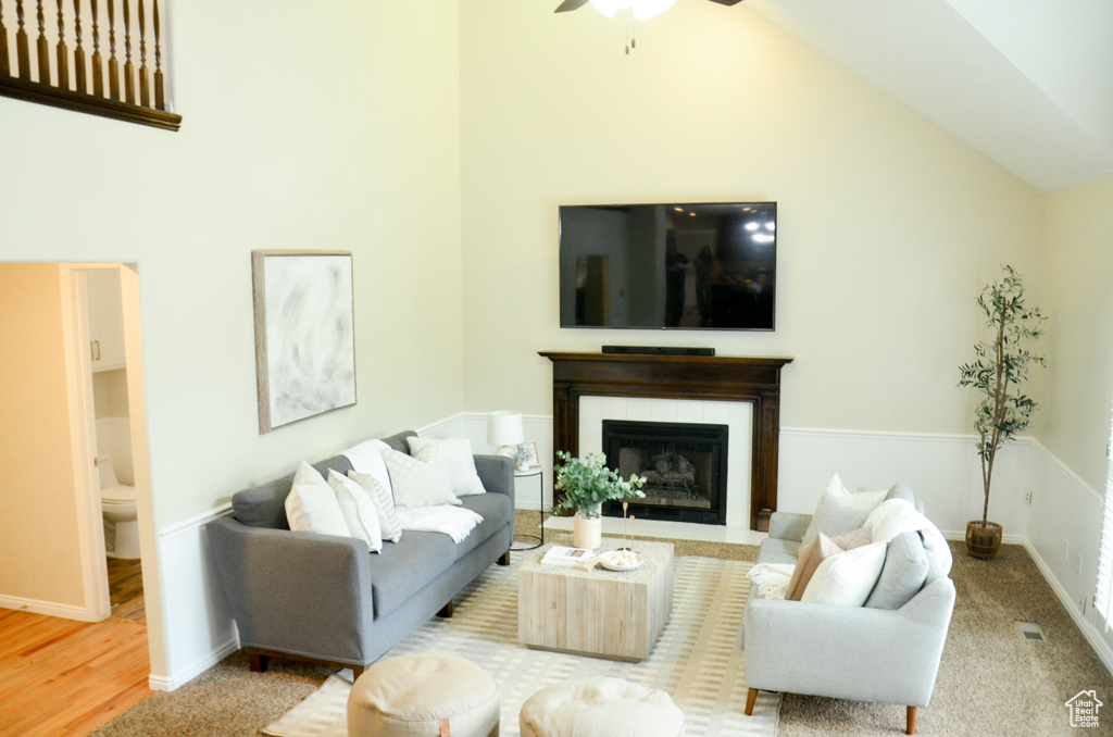 Living area featuring high vaulted ceiling, a fireplace with flush hearth, baseboards, and a ceiling fan